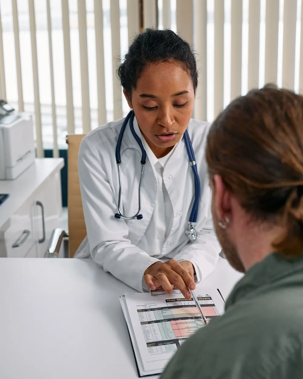 Médica de jaleco explicando um exame a um paciente